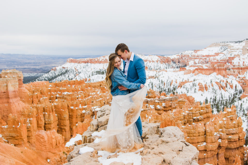 A couple cuddling up for a portrait overlooking the natural hoodoos at Bryce Canyon National Park during their elopement.