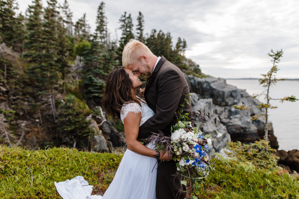 A wedding couple on a cliff for their Maine adventure elopement.