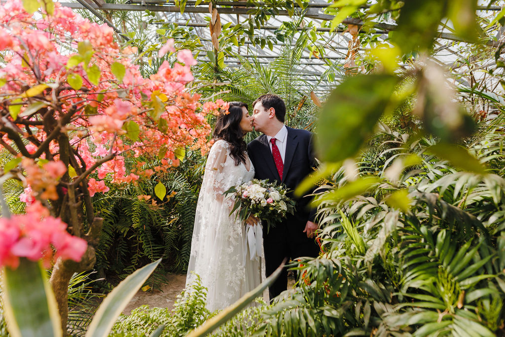 A couple in wedding attire for their tropical greenhouse elopement