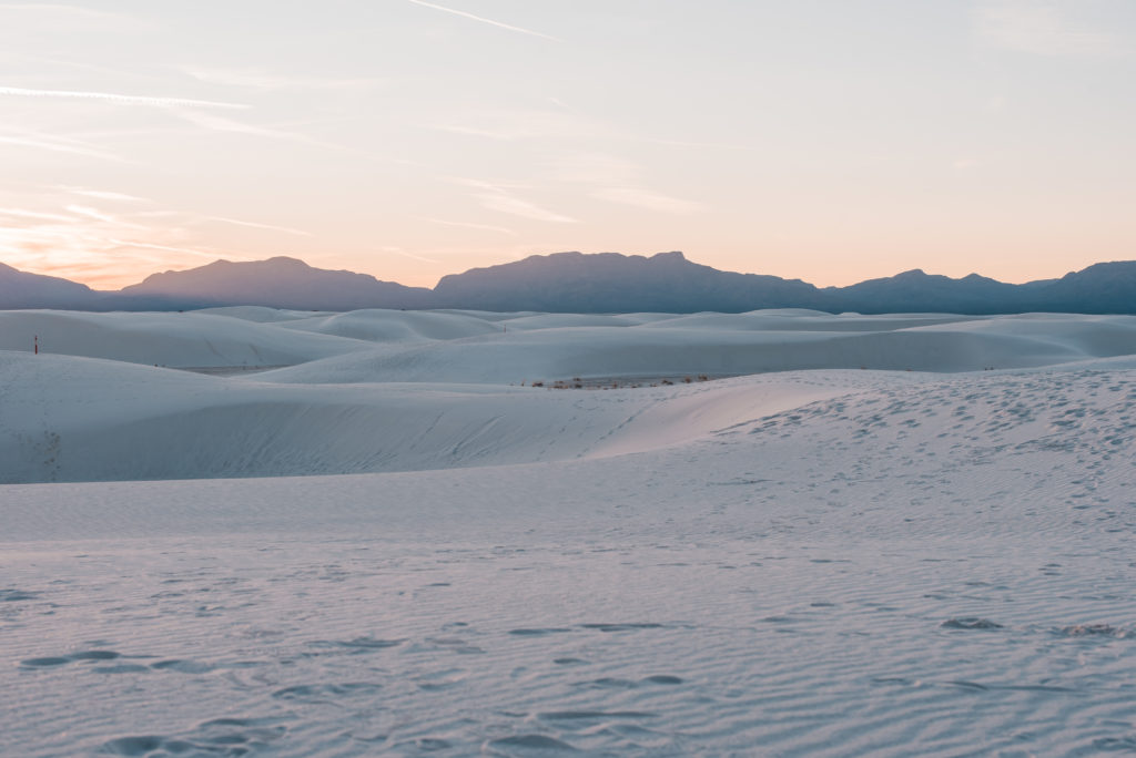 White Sand dunes in the foreground and a mountain range in the distance background.